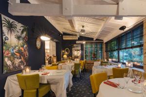 a restaurant with white tables and yellow chairs at Hostellerie du Passeur - Hôtel & Restaurant - Climatisation et Piscine chauffée in Les Eyzies-de-Tayac