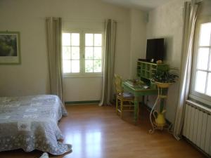 a bedroom with a bed and a desk and windows at Domaine De La Provenç'âne in Salernes