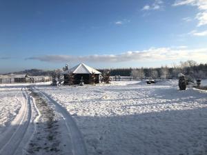 a snow covered field with a house in the background at Kantonia in Bobolice