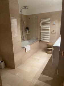 een badkamer met een douche, een bad en een toilet bij 3 bedroom luxury appartment in Klosters