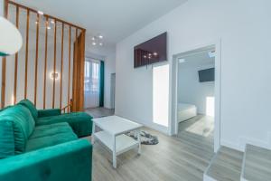 a living room with a green couch and a table at CasiAna Apartment in Râşnov