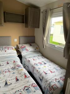 2 Betten in einem kleinen Zimmer mit Fenster in der Unterkunft ParkDean Cherry tree holiday park Burgh castle in Belton