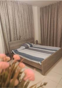 un letto in una camera da letto con tende e fiori rosa di Beautiful Master Bedroom in shared apartment ad Ajman