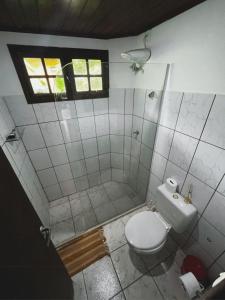 a bathroom with a toilet and a shower with a window at MangoBrazil in Imbassai
