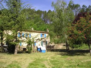 una casa de piedra con persianas azules en un patio en Domaine De La Provenç'âne en Salernes