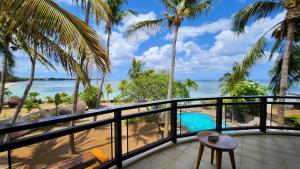 einen Balkon mit Blick auf den Strand und die Palmen in der Unterkunft La Maison de la plage in Albion