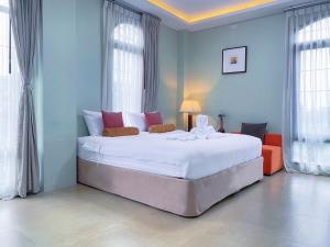 a bedroom with a large white bed with windows at Daddy Dream Hotel and Residence in Ranong