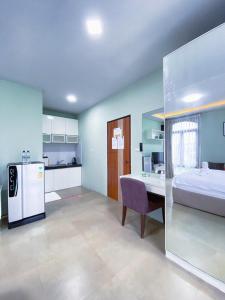 a bedroom with a bed and a table and a refrigerator at Daddy Dream Hotel and Residence in Ranong