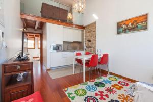 a kitchen and living room with a table and red chairs at Apartamentos Lumar in Valença