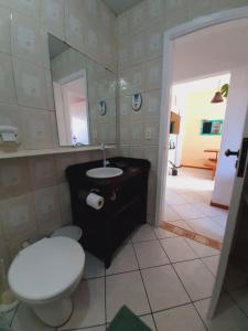 a bathroom with a toilet and a sink and a mirror at Pousada Encantos do Paraíso in Praia do Rosa +76 photos
