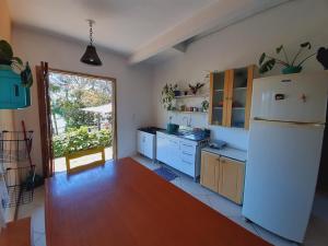 a kitchen with a white refrigerator and a large window at Pousada Encantos do Paraíso in Praia do Rosa
