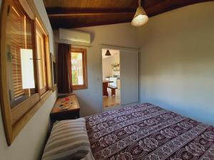 a bedroom with a bed and a table and a window at Pousada Encantos do Paraíso in Praia do Rosa