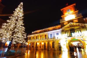 a christmas tree in front of a building with a clock tower at Leonor&Pablo in Oviedo