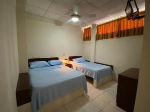 Hotel Dorado Inn في ساليناس: غرفة نوم بسريرين ومروحة سقف