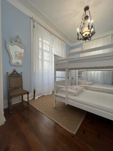 a bedroom with a white bunk bed and a chair at Casinhas no Carolina - Hostel in Porto