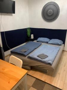 two beds with blue sheets in a room with a table at The Whistling Rabbi in Budapest