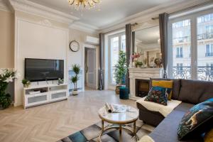 a living room with a couch and a tv at Charmant 100m2 avec 3CH - Romantique Centre Ville in Paris