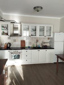 a kitchen with white cabinets and black counter tops at Бадевски рай-къща Любов in Badewzi