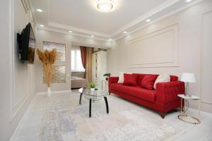 sala de estar con sofá rojo y mesa en Уютная студия на Арбате, en Almaty
