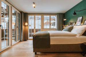 a bedroom with a large bed with a green wall at Hotel Fiescherblick in Grindelwald