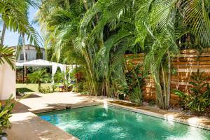 a swimming pool with palm trees next to a fence at Cafe Playa Negra Hotel in Playa Negra