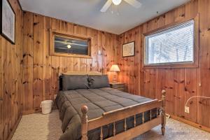 a bedroom with a bed in a room with wooden walls at Serene Woodruff Cottage Lakefront Access! in Woodruff