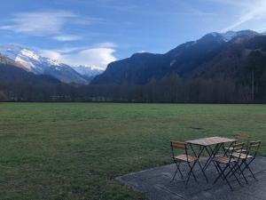 two chairs and a table in a field with mountains at Studio - Le D2 du Grand Tetras in Samoëns