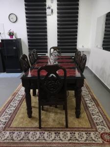 a dining room table with chairs and a table and a clock at Inap Singgah Homestay in Kota Bharu