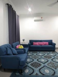 a living room with two blue couches and a rug at Inap Singgah Homestay in Kota Bharu