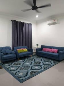 a living room with two blue couches and a rug at Inap Singgah Homestay in Kota Bharu