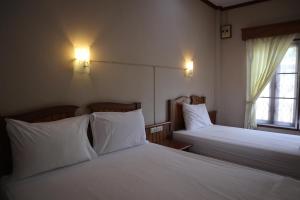 a bedroom with two beds with white sheets and a window at The Green Koh Phangan in Haad Rin
