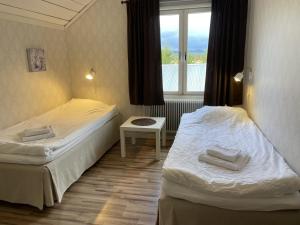 Duas camas num pequeno quarto com uma janela em Sörnäsgården Bed & Breakfast em Lima