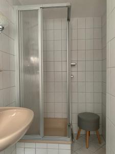 y baño con ducha, lavabo y taburete. en Ferienhaus Andrea am Bodetal, en Treseburg