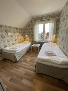 Duas camas num pequeno quarto com uma janela. em Sörnäsgården Bed & Breakfast em Lima