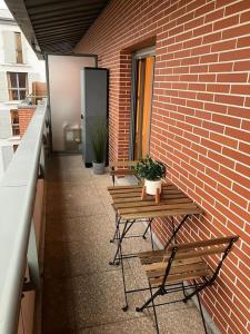 une table et deux bancs à côté d'un mur de briques dans l'établissement Studio cosy 12 min Arc de Triomphe, à Rueil-Malmaison