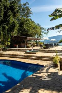a swimming pool in a resort with a table and chairs at Hotel Boutique Ananas in Ilhabela