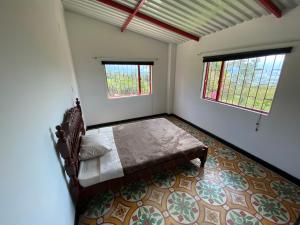 ein Schlafzimmer mit einem Bett und zwei Fenstern in der Unterkunft Casa Finca Villa Rosa - Togui in Funcional