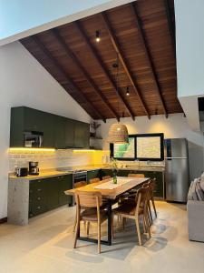 una cocina con armarios verdes y una mesa y sillas de madera. en MORADA DOS IPÊS, en Teresópolis