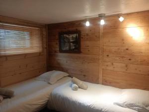 two beds in a room with wooden walls at Three Bedroomed Chalet Apartment in Chamonix
