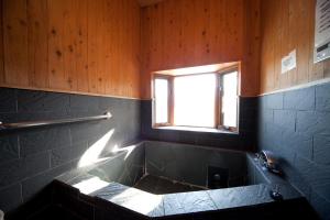 a bathroom with a bath tub with a window at Yufuin Tsukahara Kogen Sanso Donguri in Yufuin