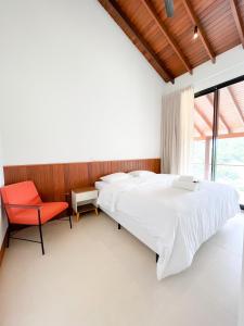 1 dormitorio con 1 cama grande y 1 silla roja en MORADA DOS IPÊS, en Teresópolis