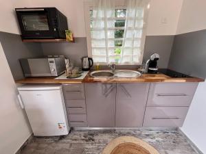 a small kitchen with a sink and a microwave at Bienvenue chez Angie in Les Abymes
