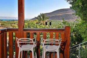 two chairs on a porch with a view of the mountains at עדנת האוהבים - סוויטות מקסימות ליד הכנרת עם בריכה משותפת in Migdal