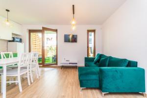 a living room with a green couch and a table at Baltic Park Szmaragdowa fala in Stegna