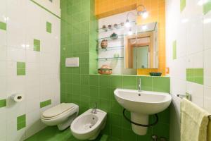 een groene en witte badkamer met een wastafel en een toilet bij La Camelia Apartment in Sorrento