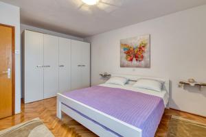 sypialnia z dużym łóżkiem z fioletową pościelą w obiekcie Apartment Ana Coki w mieście Funtana