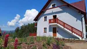 een wit huis met een rood balkon en bloemen bij APARTMáN POD SMRČINOU in Vaclavov u Bruntalu