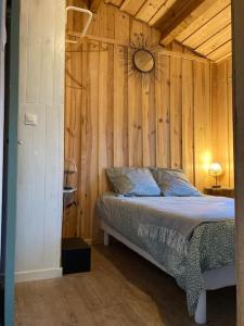 - une chambre avec un lit et un mur en bois dans l'établissement Cabane de charme en pleine forêt - Domaine Temali, à Labouheyre