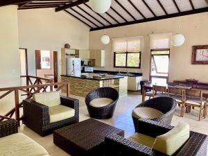 a living room with wicker chairs and a kitchen at Casa Pé na Areia - Jacumã, Vista Mar, Wi-Fi by PenareiaTurBr in Conde
