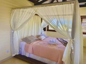 a bedroom with a canopy bed with white curtains at Casa Pé na Areia - Jacumã, Vista Mar, Wi-Fi by PenareiaTurBr in Conde